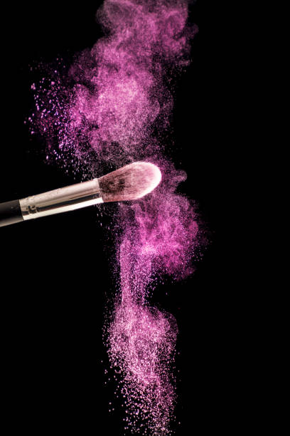 istock Make up brush with purple dust powder explosion isolated on black background 1047849766