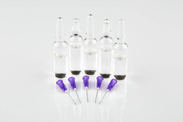 istock Ampoules and violet syringe needles on white background 1047852766