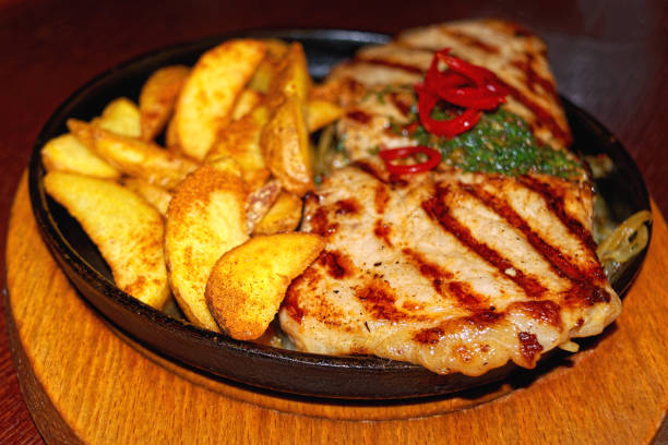 istock Big pork steak with fried potatoes in a cast iron pan 1047869028