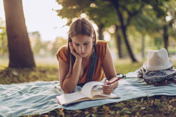 istock Cute woman reading in park 1047871484