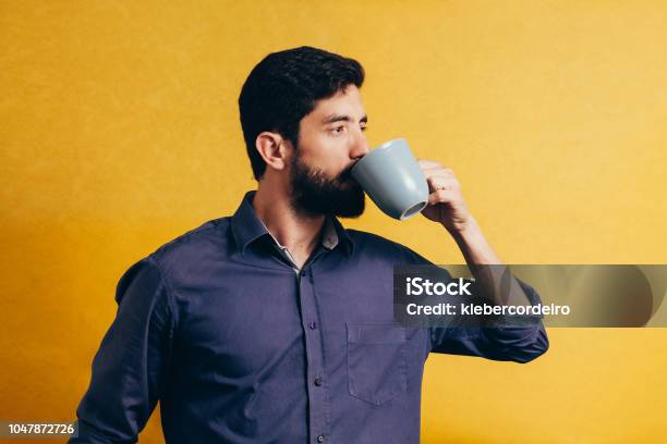 Portrait Of Handsome Man Drinking Coffee Over Yellow Background Stock Photo - Download Image Now