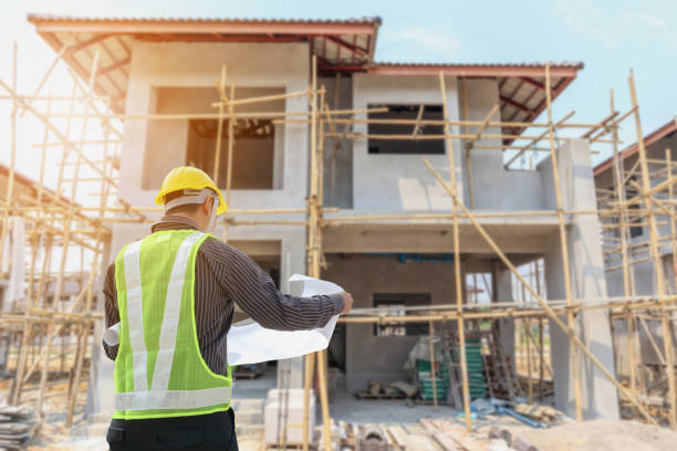istock Professional engineer architect worker with protective helmet and blueprints paper at house building construction site 1047876120