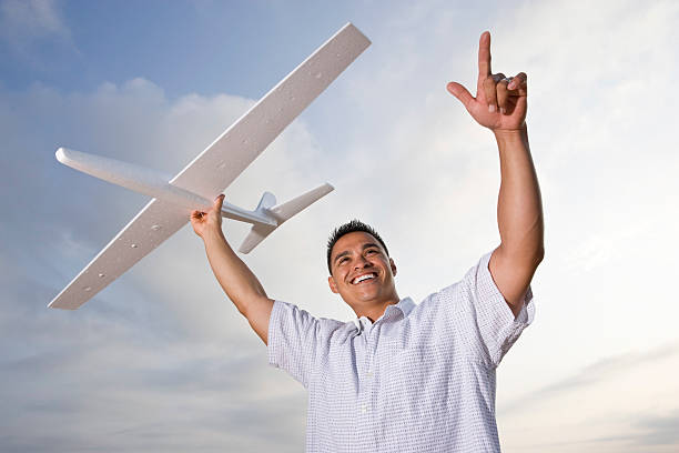 istock Hispanic man holding model airplane glider over head 104789090