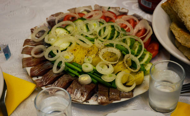 Russian snack, fish, tomato, cucumber, potatoes, onions, green onions in a white plate. stock photo