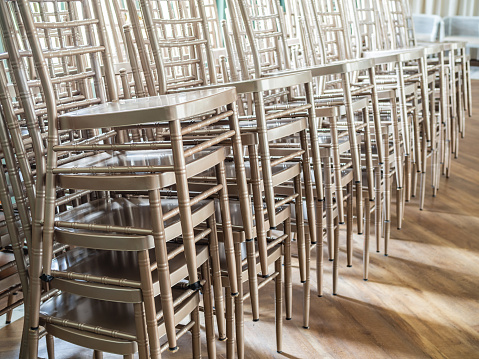 Rows of modern stacked silver chairs on wooden floor with the light from outside from the window.