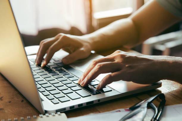 istock Man working at home office using a laptop computer on wooden table. Hands typing on a keyboard. 1047957584