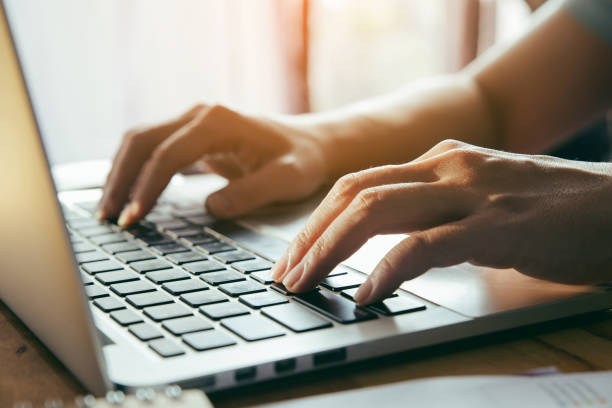 istock Close up fingers typing on the computer keyboard,pressing buttons, typing, simple close up with lens flare 1047957974