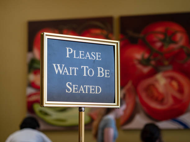 пожалуйста, подождите, чтобы сидеть знак, стоящий в передней части ресторана - restaurant dinner waitress dining стоковые фото и изображения
