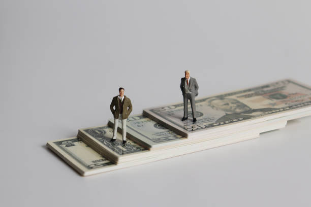 istock Two miniature men standing on a pile of bills. 1047980166