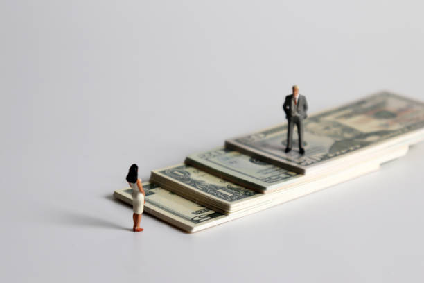 A miniature man and a miniature woman standing on a pile of bills. stock photo