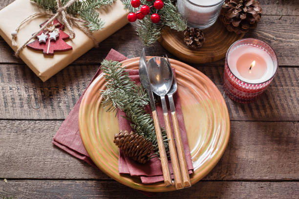 istock Christmas Setting Table. Dinner plate, silverware, fir tree, gift boxe, candle and festive decoration. Holiday Food Concept. Top view 1047980830