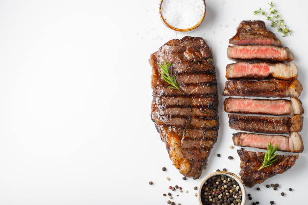 istock Two grilled marbled beef steaks striploin with spices isolated on white background, top view with copy space 1048000226