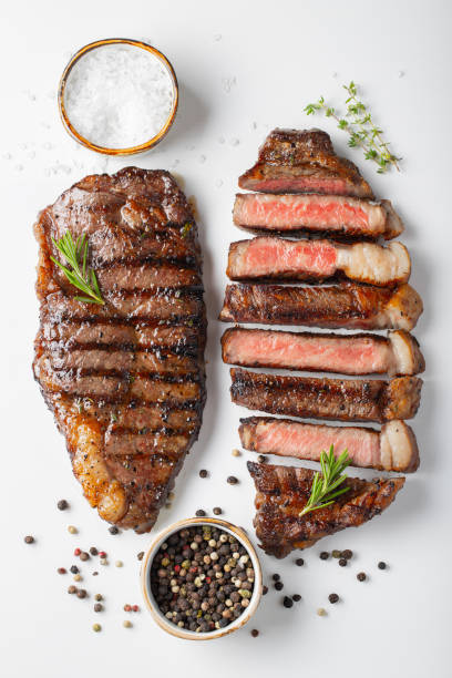 istock Two grilled marbled beef steaks striploin with spices isolated on white background, top view 1048000230