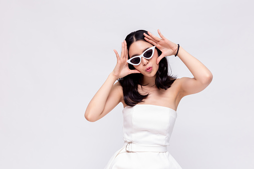 Elegant and attractive Asian chic fashion woman in stylish white dress with sunglasses in isolated background