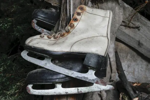 Very old white and black rusty and dirty ice skates hanging in warehouse