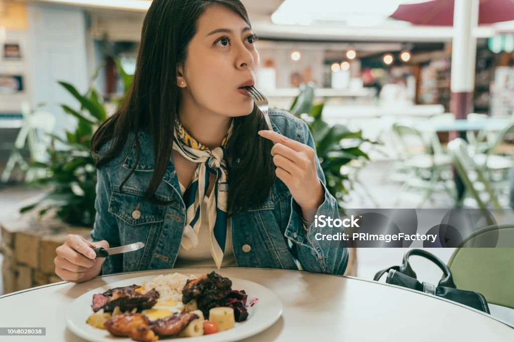 beautiful lady sitting outdoor and having lunch beautiful lady sitting outdoor and having lunch, she is putting food in her mouth, and looking at someone else who walks by Chewing Stock Photo