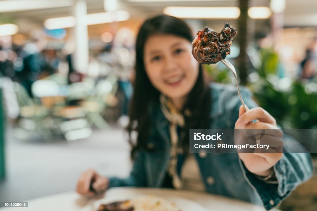 pretty woman showing her delicious food pretty woman using fork to show her delicious food, she is giving the camera a big attractive smile Adult Stock Photo