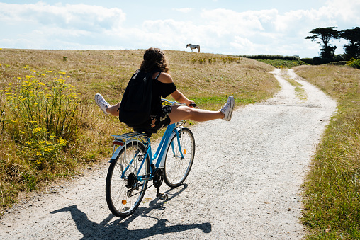 Pretty young woman riding bicycle in a country road with her legs in the air