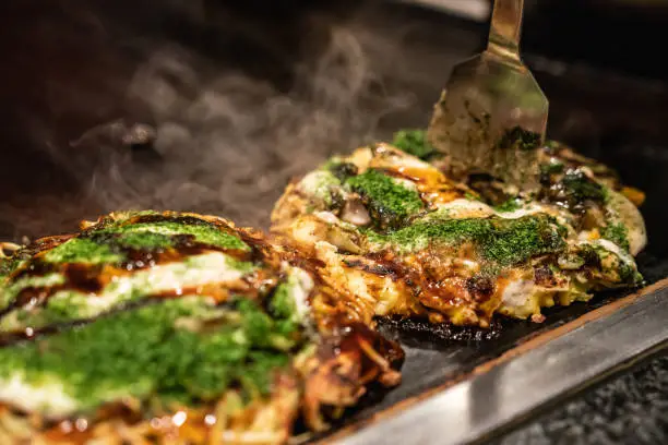 Photo of chef use spatula to cut okonomiyaki