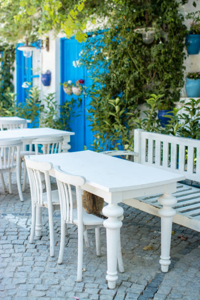 casas tradicionales antiguas y tradicionales mesas blancas y sillas en grecia. - greek islands table window sun fotografías e imágenes de stock