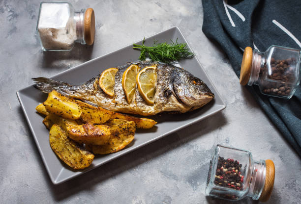 istock Grilled fish on stone plate with lemon on concrete background 1048037288