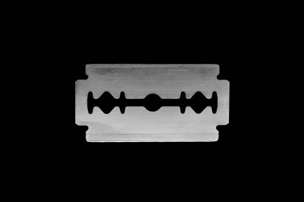 istock Close up view of metallic razor blade isolated on black background surface 1048056794