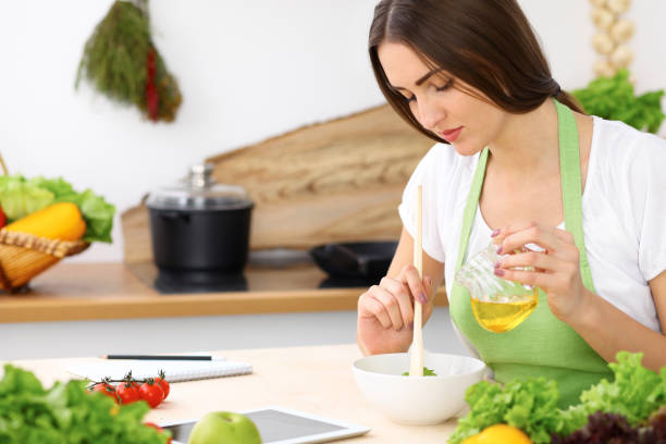 istock Beautiful Hispanic woman cooking while using tablet computer in kitchen. Housewife found new recipe for dinner or breakfast. 1048060406