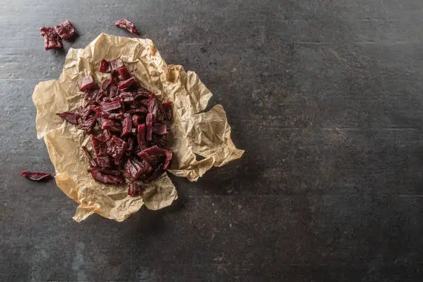 A pile of dried beef jerky pieces on paper and cutting board.