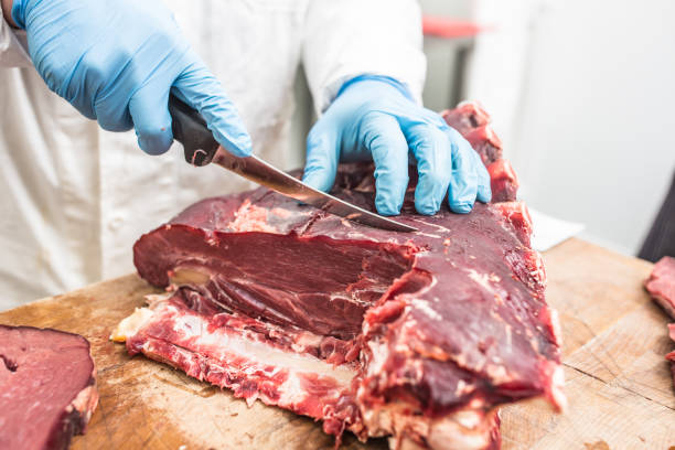 istock Worker from knife cutting  meat in a meat shop. 1048065078