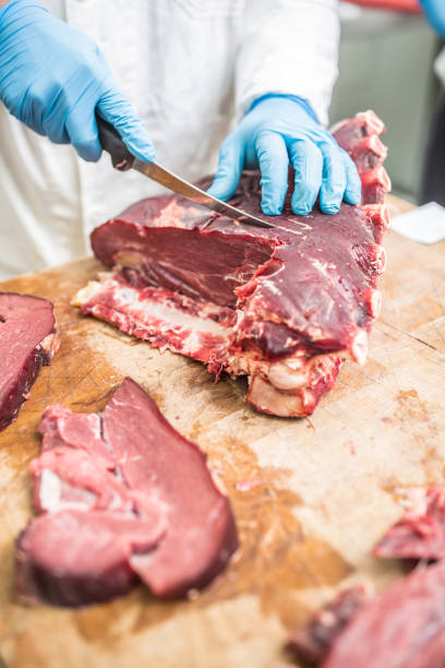 istock Worker from knife cutting  meat in a meat shop. 1048065090