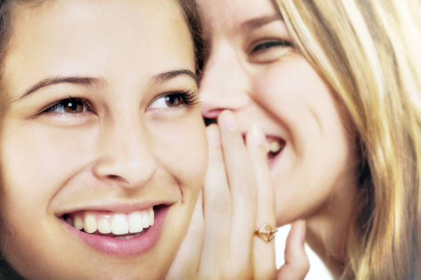 istock Two giggling girlfriends happily whispering scandalous secrets 1048078746