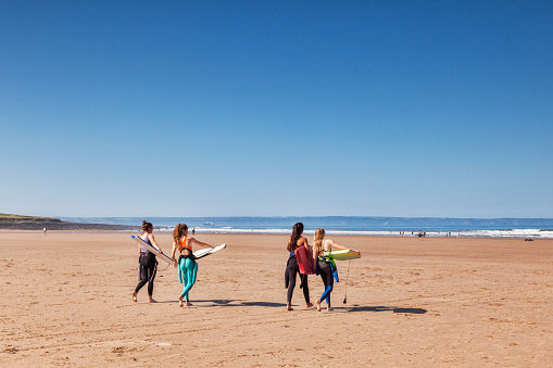 18 June 2017: Croyde Bay, North Devon, England, UK - Four young women approch the sea with surf boards on one of the hottest days of the year.