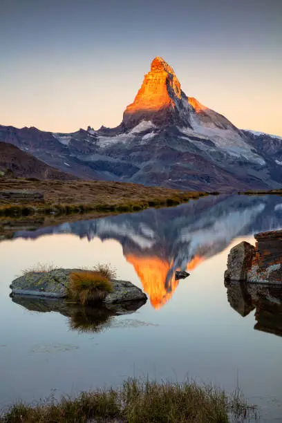 Landscape image of Swiss Alps with Stellisee and Matterhorn in the background during sunrise.