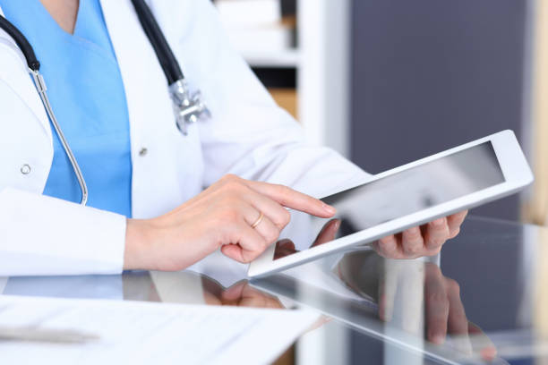 istock Woman doctor using tablet computer while standing straight in hospital office, closeup. Healthcare, insurance and medicine concept. 1048083356