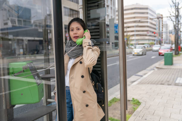 かなり女性観光公衆電話を使用して - pay phone ストックフォトと画像