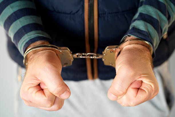 istock Criminal hands locked in handcuffs. Close-up view 1048094386