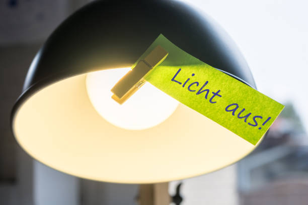 Desk lamp with sticky note with the reminder in german to turn off the light reminder, notes desk lamp photos stock pictures, royalty-free photos & images