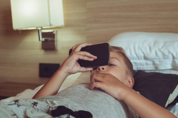 istock Small boy watching cartoons on smart phone while lying on the bed. 1048099142