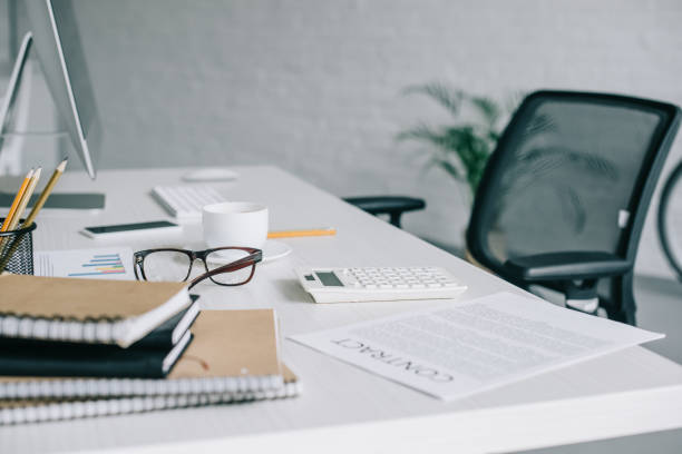 istock notebooks, contract, calculator and glasses on table in light modern office 1048099388
