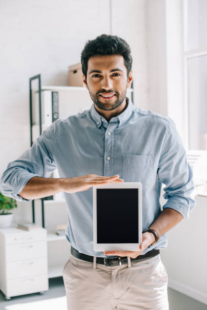 istock handsome smiling architect showing tablet with blank screen in office 1048099686