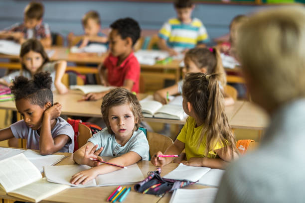 istock Elementary students listening to their teacher on a class. 1048100072