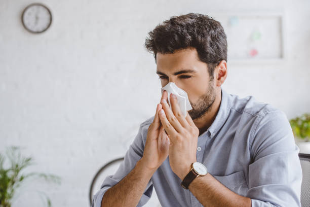 istock sick manager blowing nose in tissue in office 1048100946