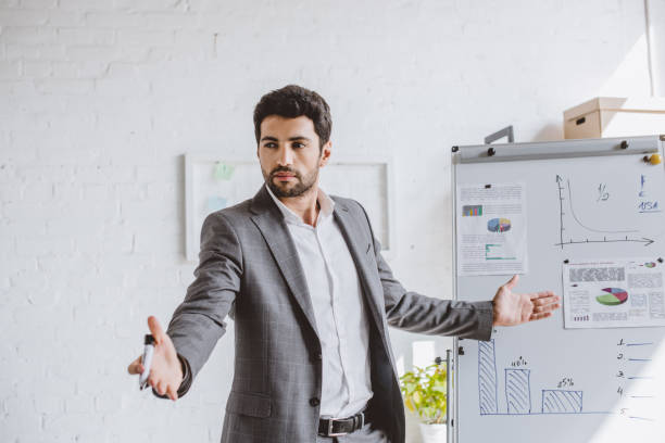 istock handsome businessman presenting project on flipchart and gesturing in office 1048102592
