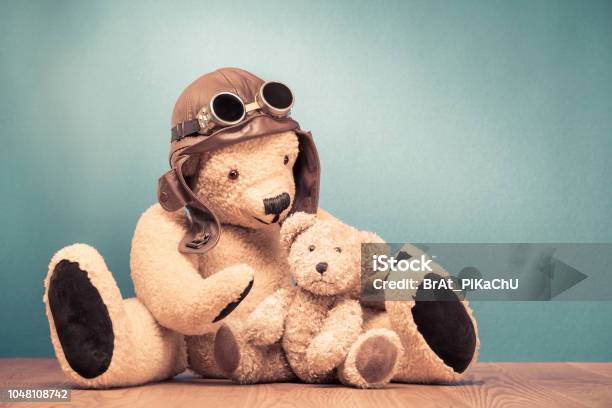 Retro Teddy Bear Toy In Leather Pilots Hat And Vintage Goggles Playing With Baby Front Mint Green Wall Background Old Style Filtered Photo Stock Photo - Download Image Now