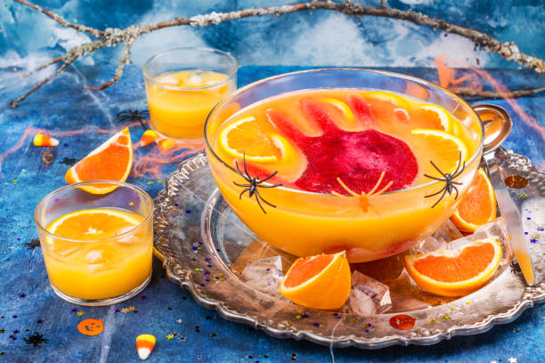 Ghoul's punch in a glass bowl Ghoul's orange punch with bloody ice hand in a glass bowl on dark halloween background punch drink stock pictures, royalty-free photos & images
