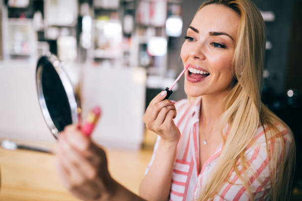 istock beautiful young woman applying lips makeup 1048110554