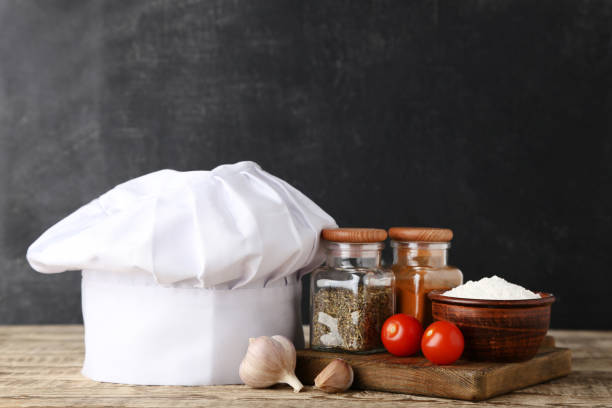 istock Chef hat with vegetables and spices in jars on wooden table 1048119968