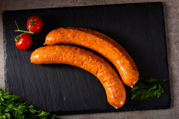 istock Two smoked pork sausages with herbs and sherry tomatoes on a dar slate 1048121534