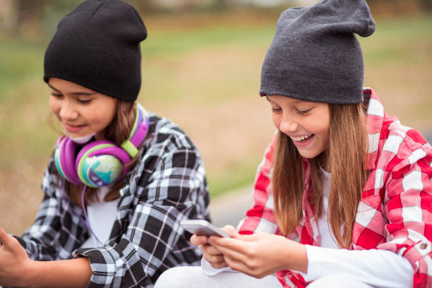 istock Two smiling little girls using mobile phones 1048121756