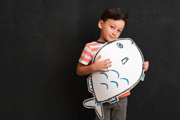 istock Cute child holding fish drawing. 1048132478